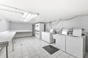 Laundry facility with white machines and folding tables